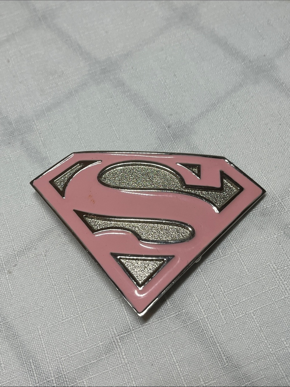 DC Comics Supergirl logo belt buckle
pink enamel
metallic base 
Supergirl 'S’